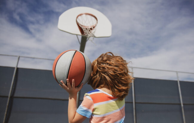 Little child boy playing basketball with basket ball. Basketball kids school. Jugar basquetbol ayuda a crecer